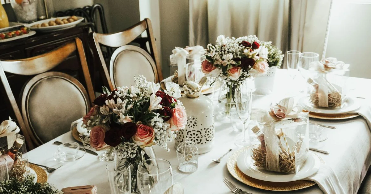Table à manger magnifiquement décorée avec des bouquets de fleurs et des boîtes-cadeaux, disposée élégamment pour une réception.