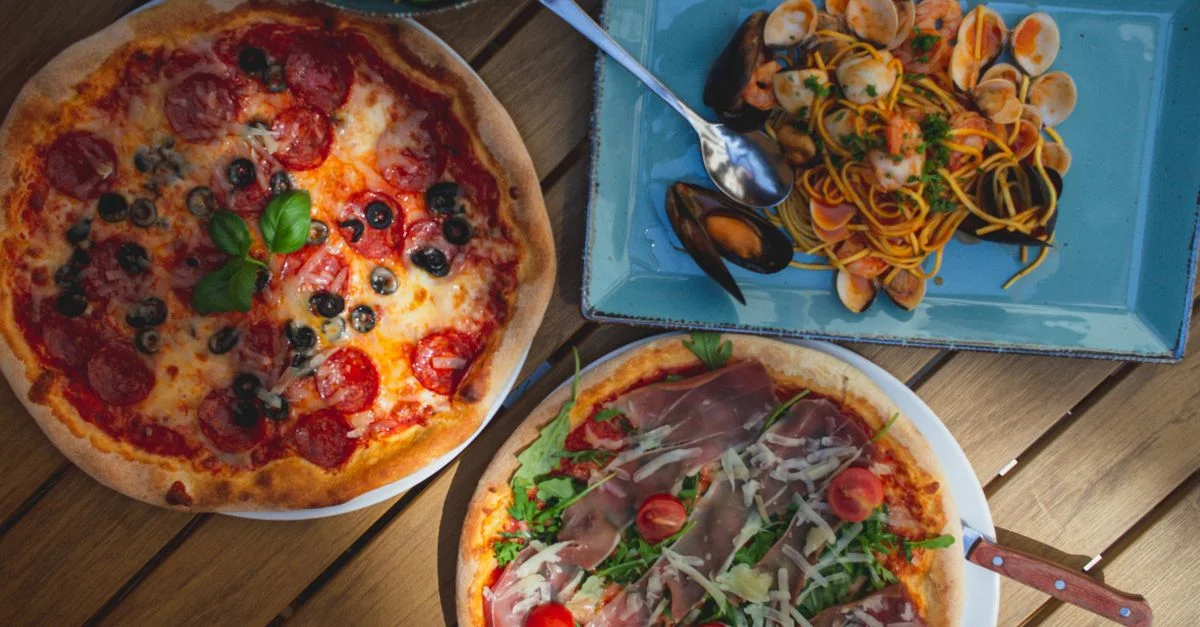 Vue de dessus de délicieuses pizzas et de pâtes aux fruits de mer, parfaites pour les amateurs de cuisine italienne. Capturé à la lumière naturelle.