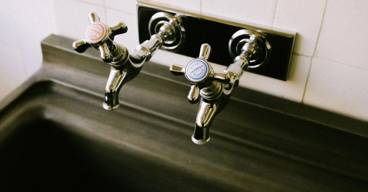 Vue détaillée des robinets chromés avec des étiquettes classiques pour l'eau chaude et froide dans un cadre de cuisine.