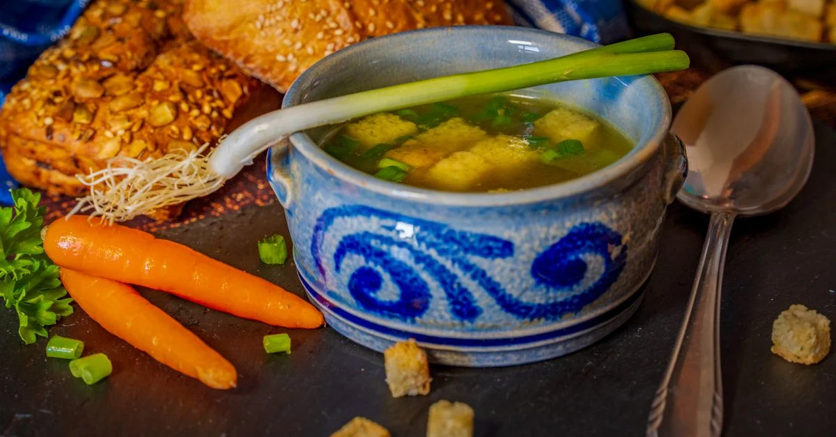 Bol chaleureux de bouillon de légumes avec croûtons et pain, parfait pour le confort d'hiver.
