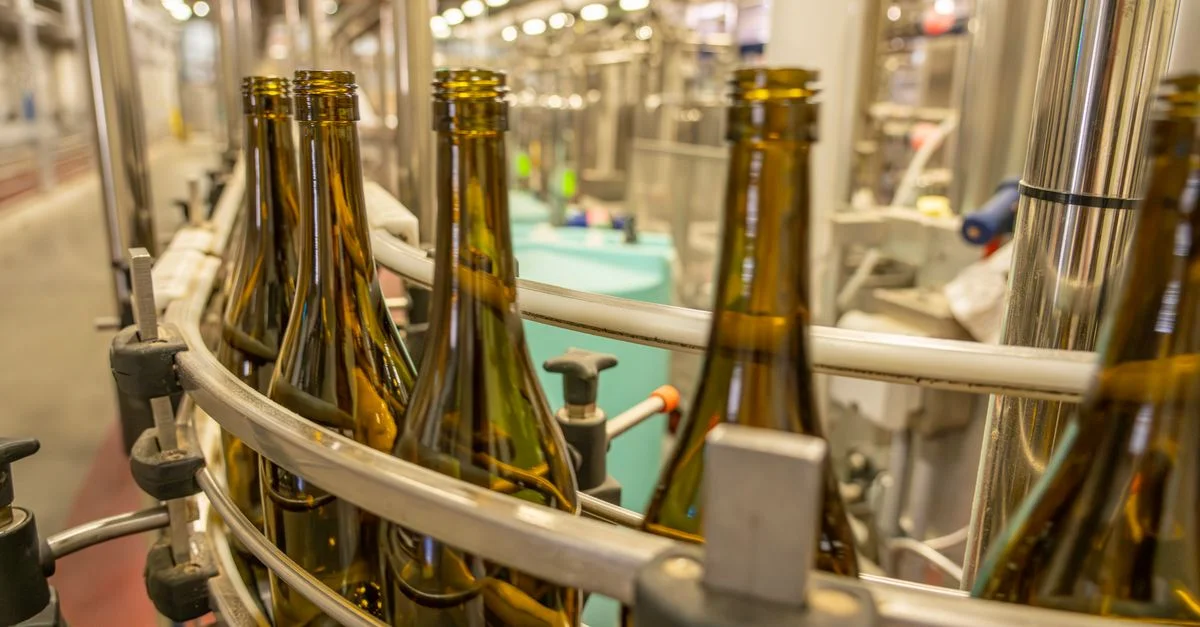Vue en gros plan de bouteilles en verre sur une ligne de production industrielle dans une installation de fabrication.