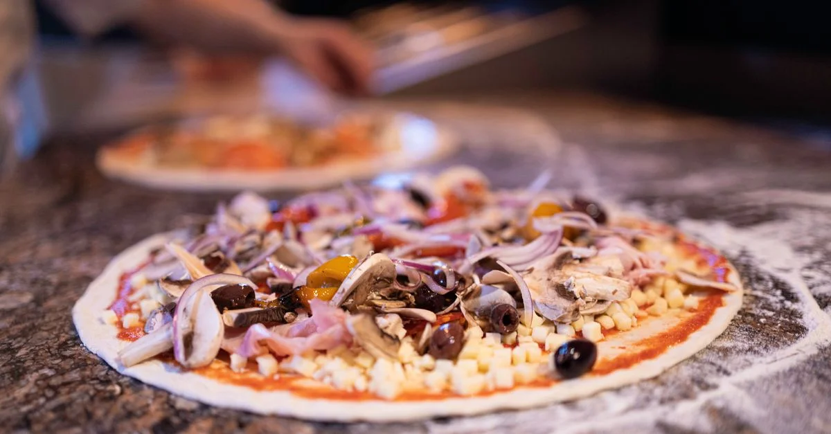 Délicieuse pizza garnie de légumes frais et d'olives sur un plan de travail en pierre.
