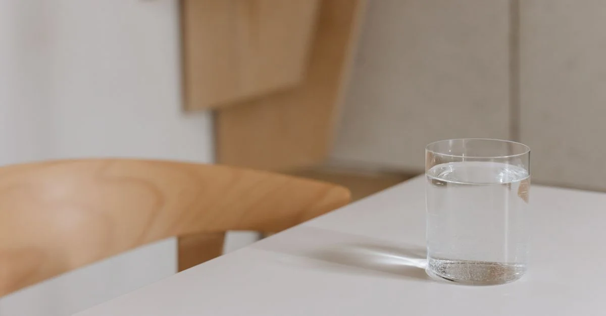 Composition simple et élégante d'un verre d'eau sur une table en bois moderne à l'intérieur.