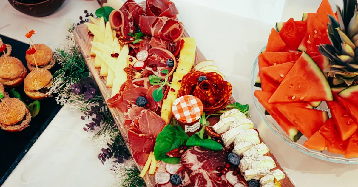 Planche de charcuterie appétissante composée de viandes, de fromages et de tranches de fruits frais pour une collation gourmande.