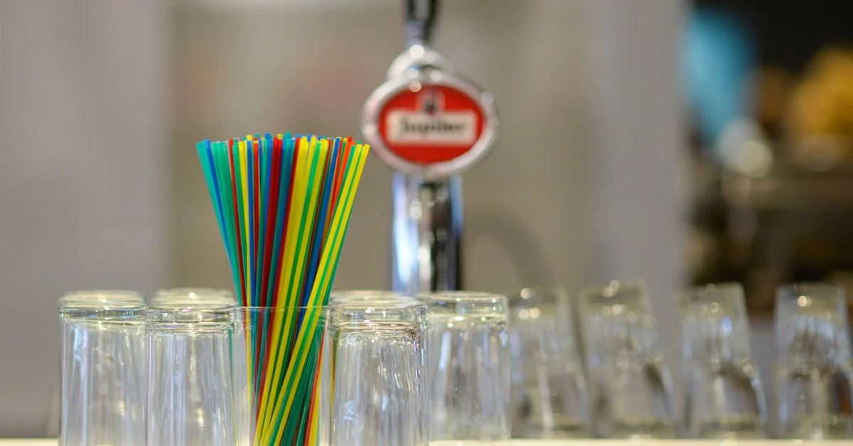 Des pailles vibrantes et des verres à l'envers sur un comptoir de bar avec un arrière-plan flou.