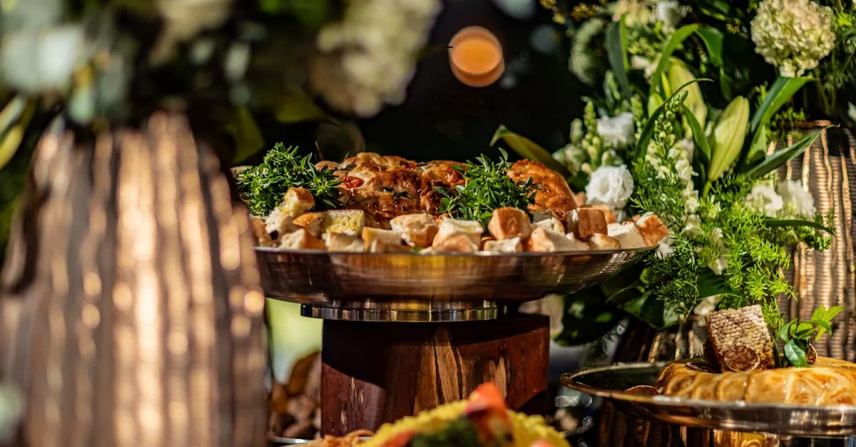 Élégant buffet gourmet avec viandes et pains, entouré de arrangements floraux vibrants créant une ambiance savoureuse.