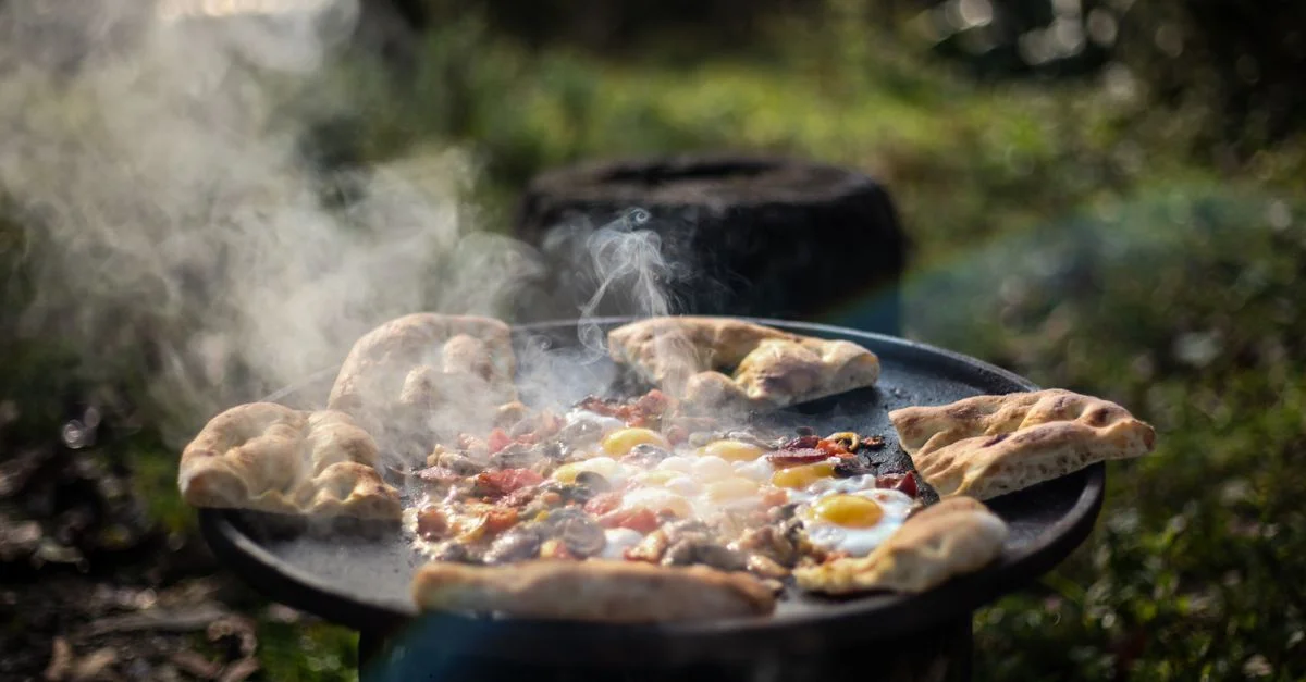 Scène de cuisine en plein air délicieuse avec des œufs et du pain plat dans une poêle en fonte avec de la fumée.