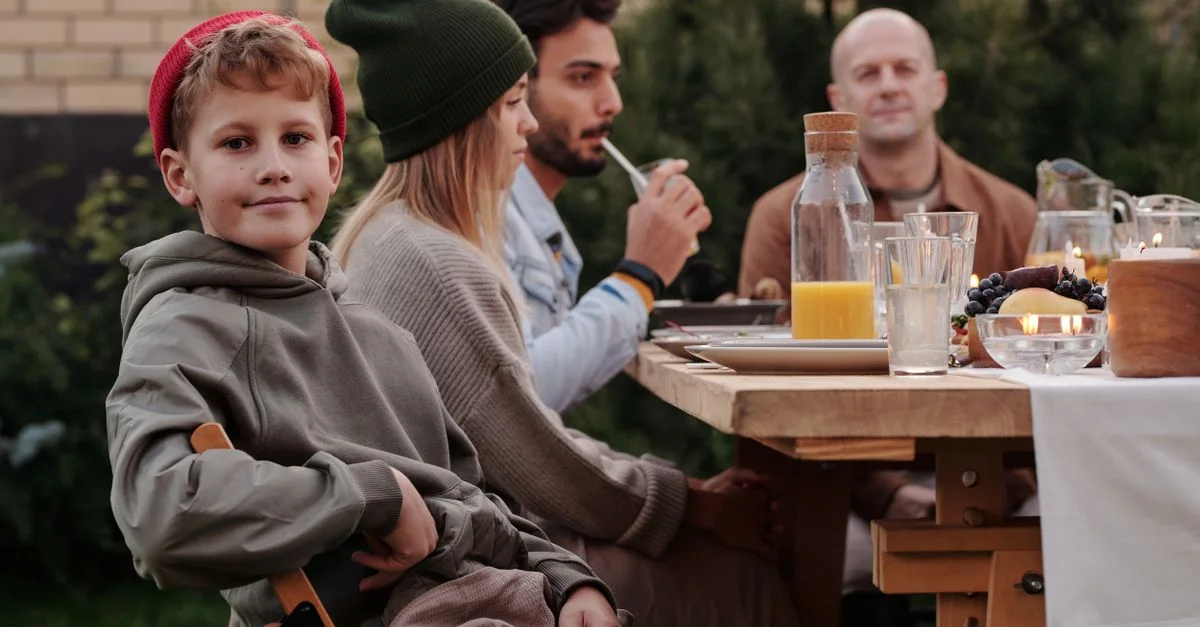 Une famille multigénérationnelle profitant d'un repas en plein air ensemble avec des boissons et des rires.