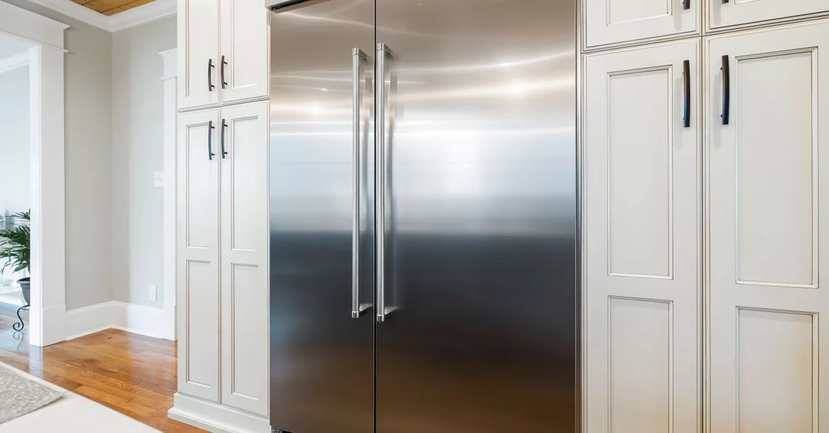 Réfrigérateur en acier inoxydable élégant au milieu d'un mobilier raffiné dans une cuisine lumineuse.