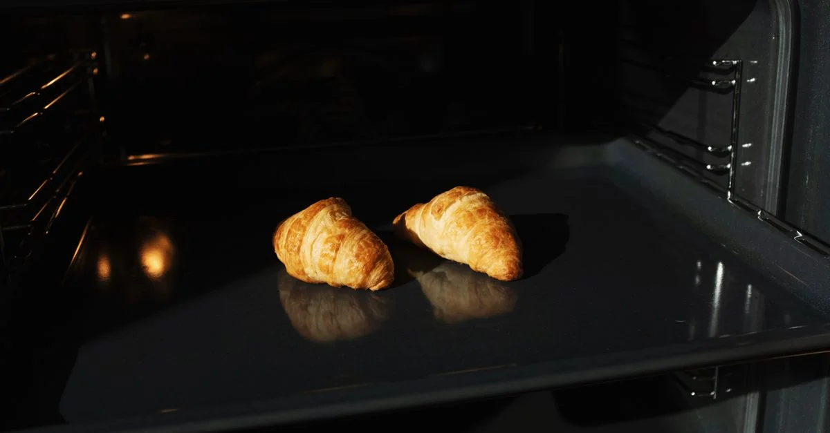 Des croissants dorés cuisant dans un four, capturant le parfait moment de pâtisserie fait maison.