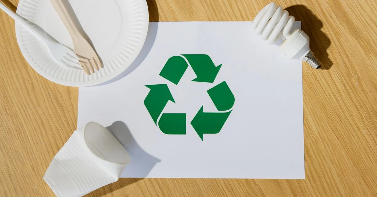 Ustensiles écologiques, ampoule et symbole de recyclage sur du papier soulignent un mode de vie durable.