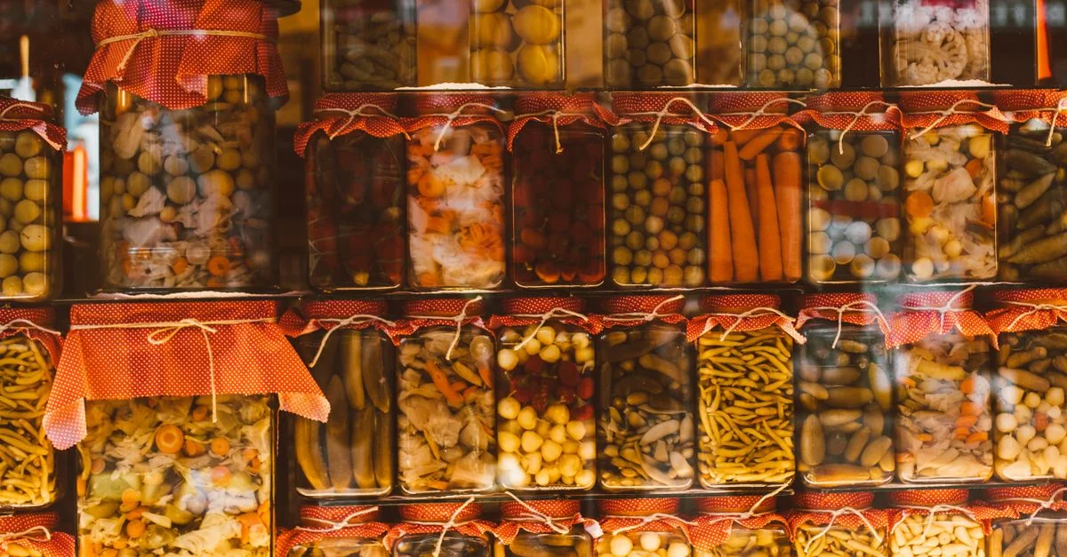 Rangs de légumes colorés conservés dans des bocaux en verre, mettant en avant la variété et l'abondance.