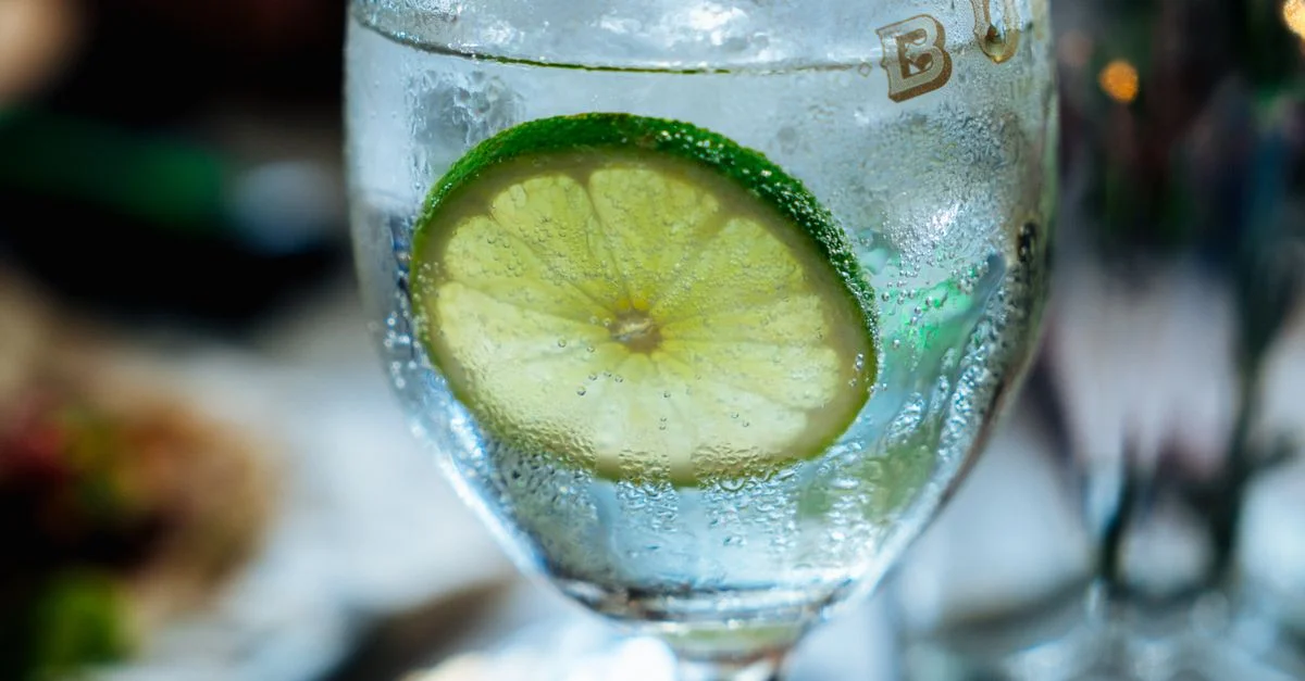 Gros plan sur une tranche de citron vert rafraîchissante dans un verre d'eau glacée, parfait pour étancher la soif.